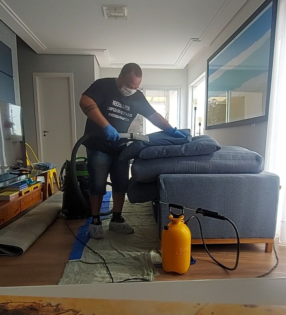 Profissional da Neide Maria higienizando sofá estofado no local