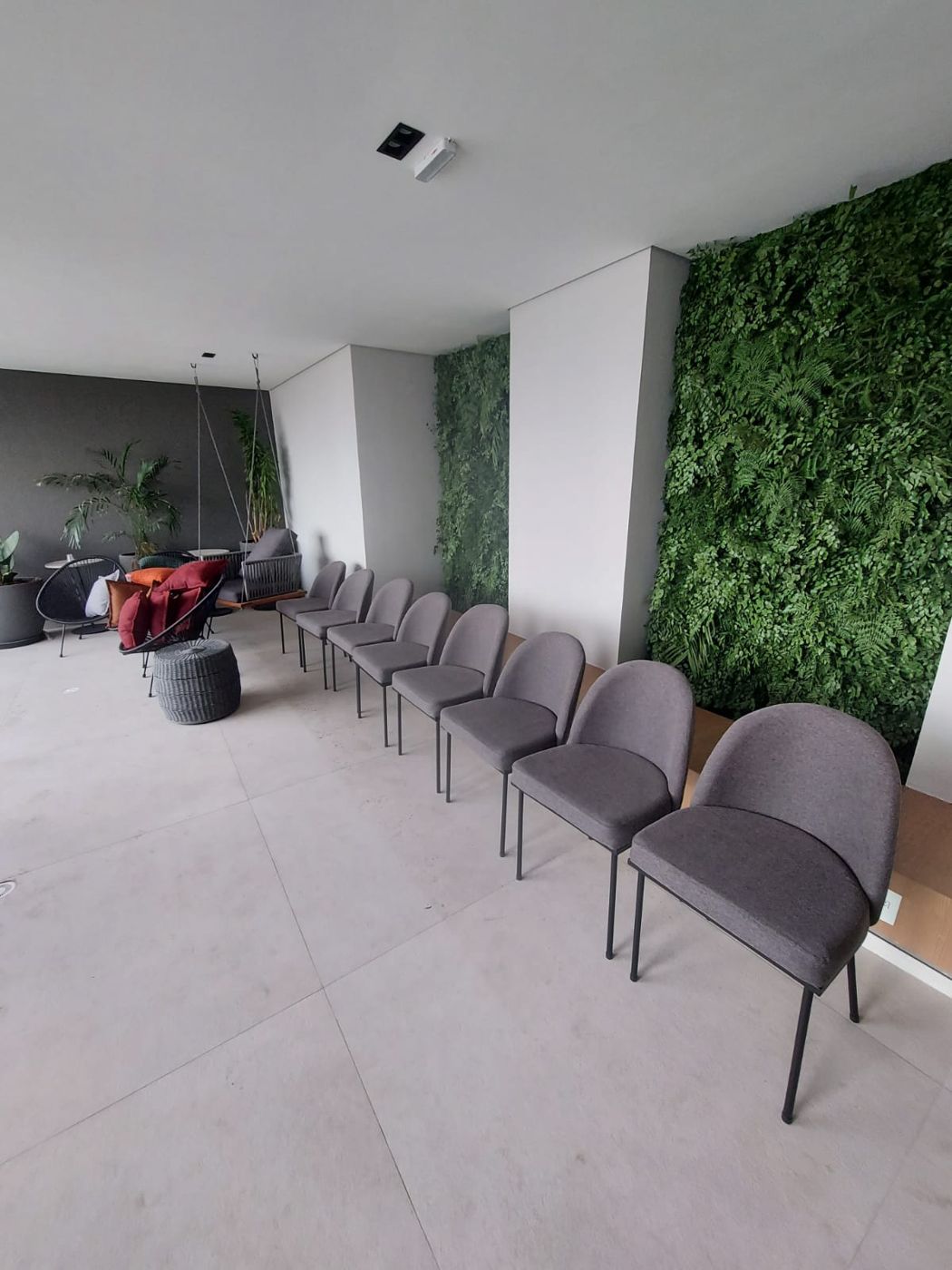Sala de espera com fileira de cadeiras estofadas e parede verde