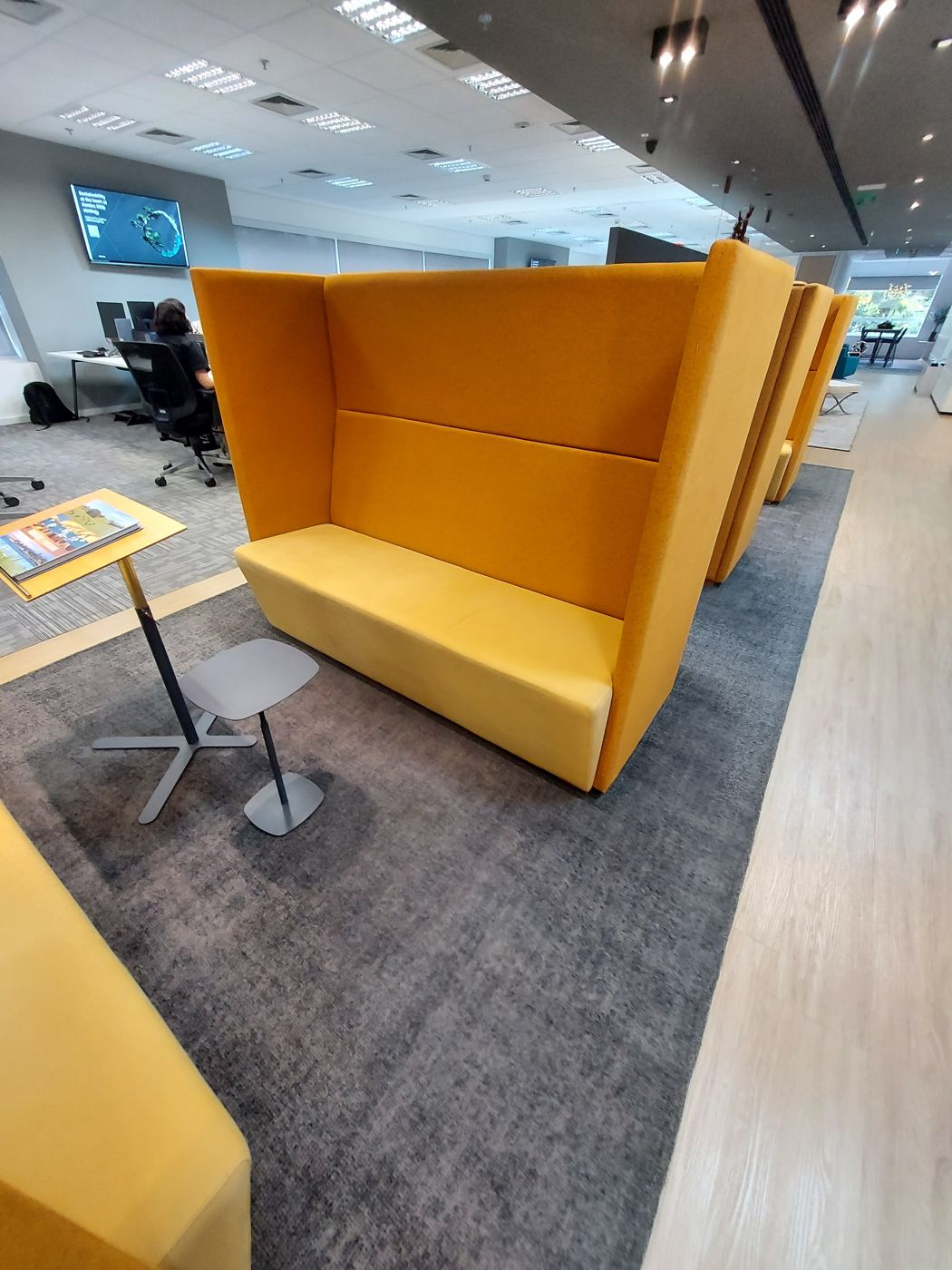 Coworking com cabines estofadas amarelas e carpete