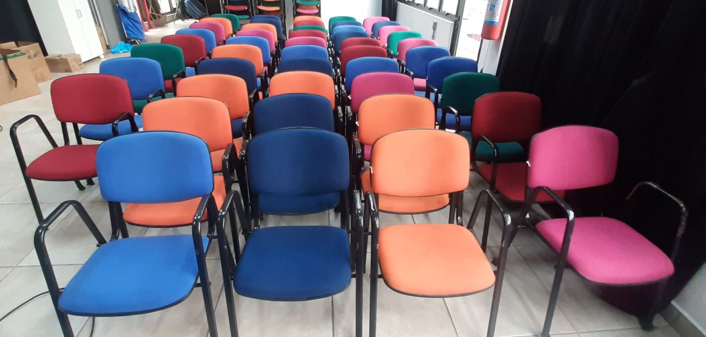 Auditório com fileiras de cadeiras estofadas coloridas