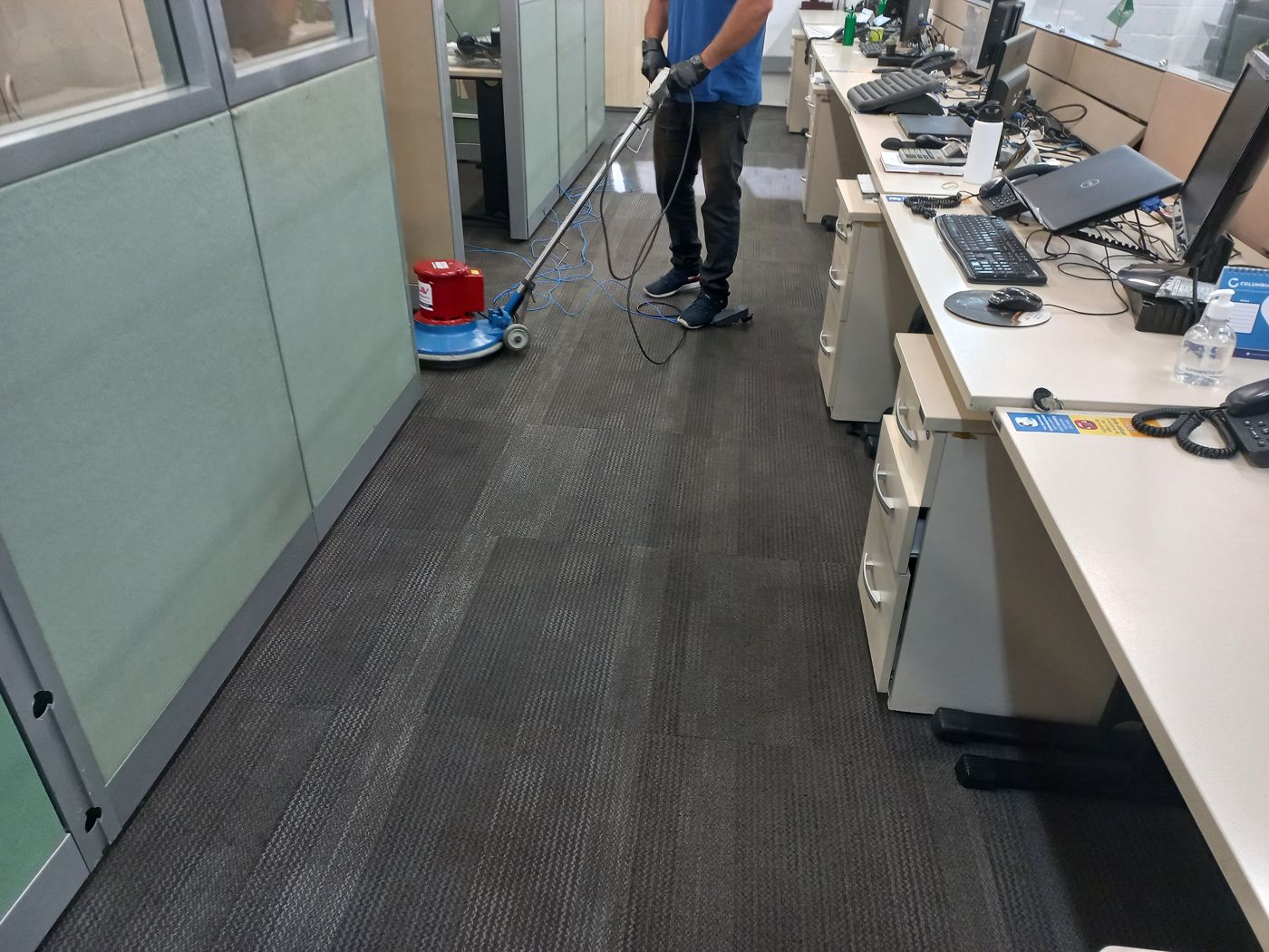 Profissional da Neide Maria higienizando carpete de corredor com enceradeira