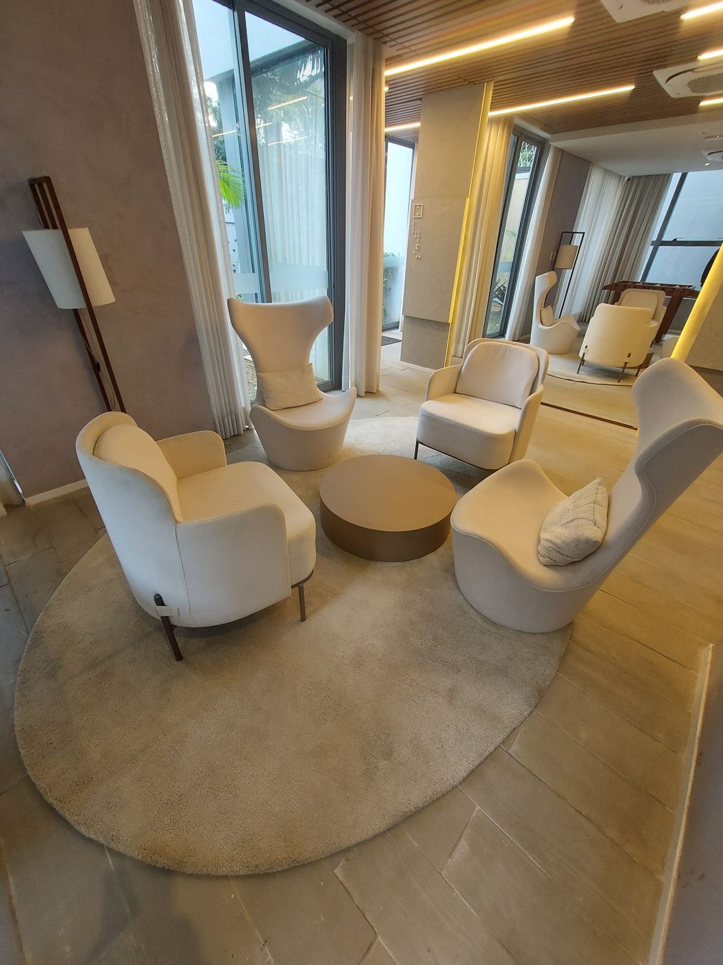 Lounge de hotel com poltronas brancas e tapete redondo